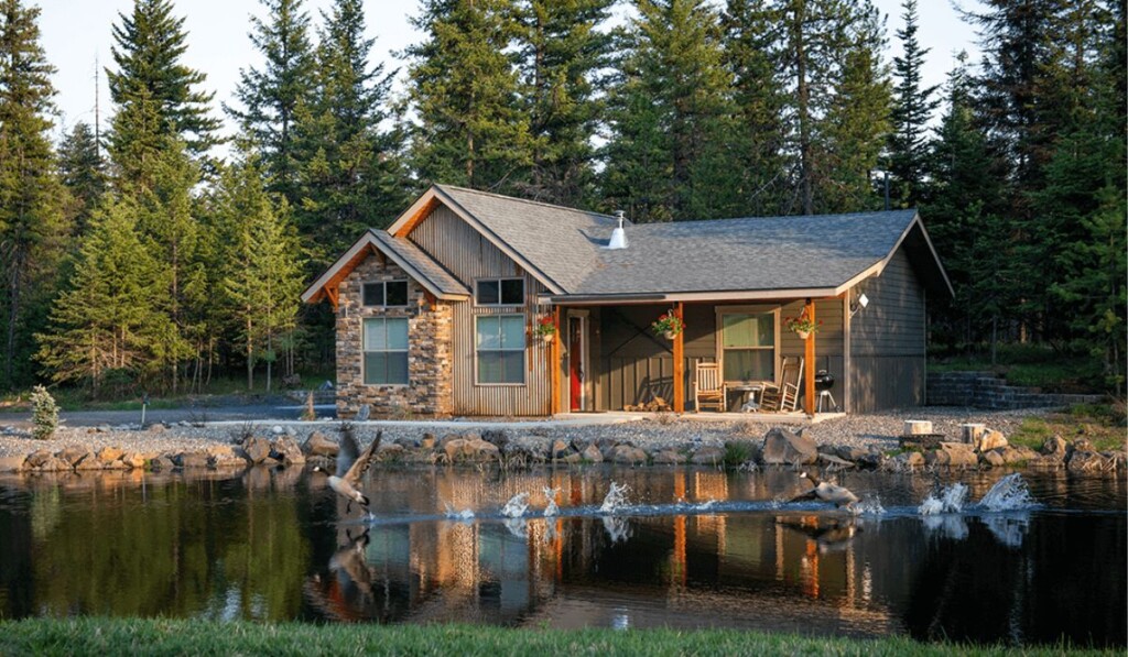 cabin on a lake with pine trees in the background