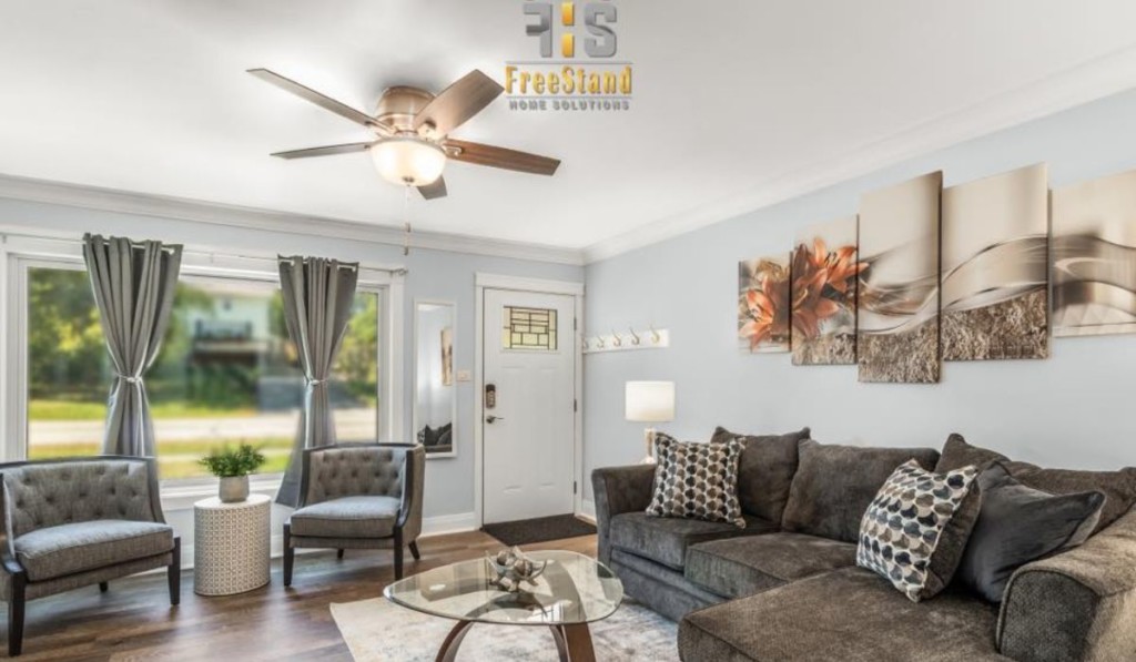 a living room filled with sofas, chairs, frames, and a ceiling fan with FreeStand Home Solutions' logo on the image